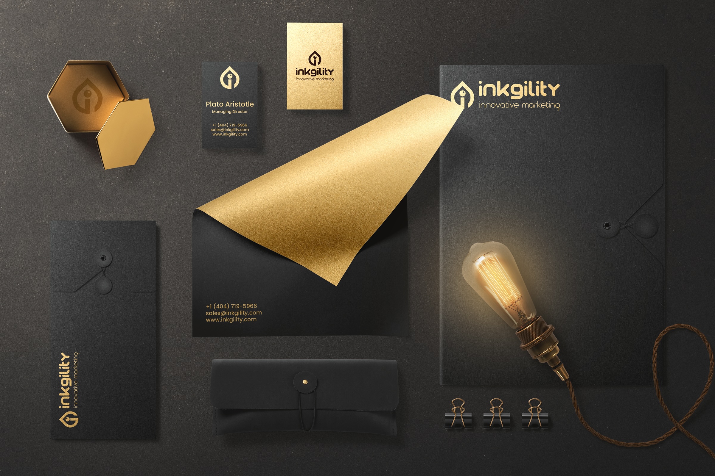 Inkgility marketing agency brand identity system in black and gold foil: business cards, letterhead, envelope, folder, and stationery mockup
