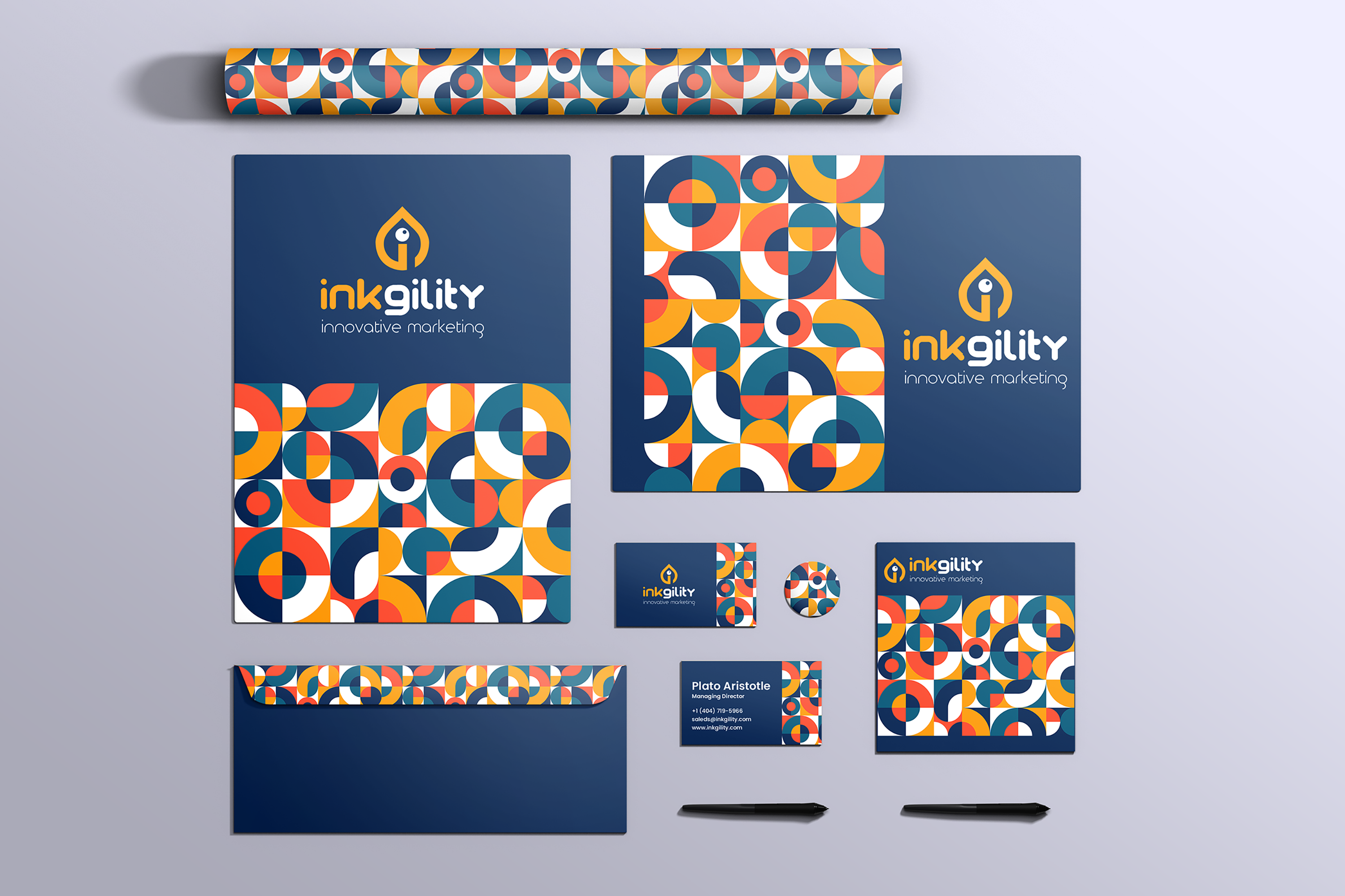 Inkgility logo mark construction, wireframe geometry sketched on a clipboard alongside pens, pencils, ruler, watch, and business card