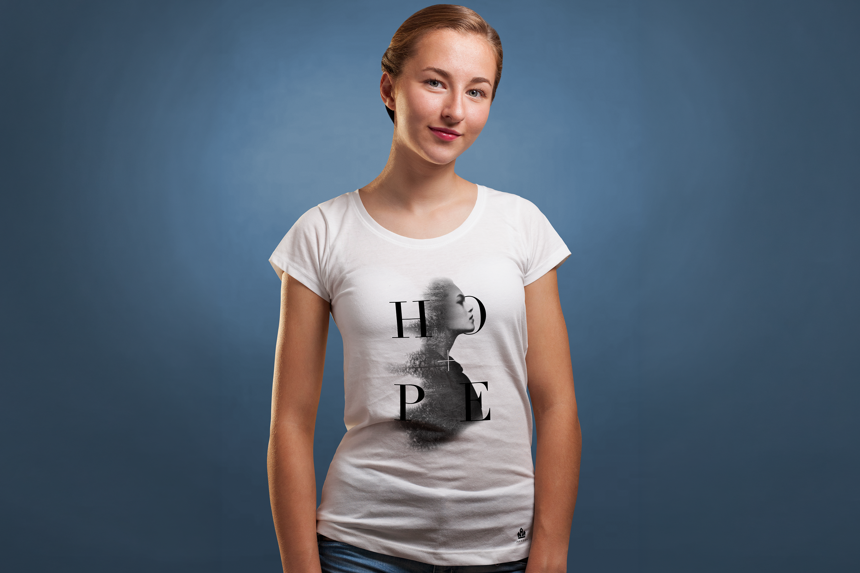 Female model in white Inknoda tee against dark navy backdrop wearing the HOPE typographic design with a double-exposure portrait masked inside the letterforms